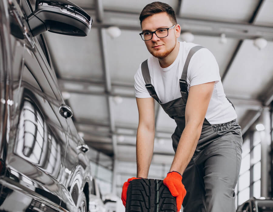 Mécanicien professionnel préparant la pose d'un pneu au Garage MS à Beaumont